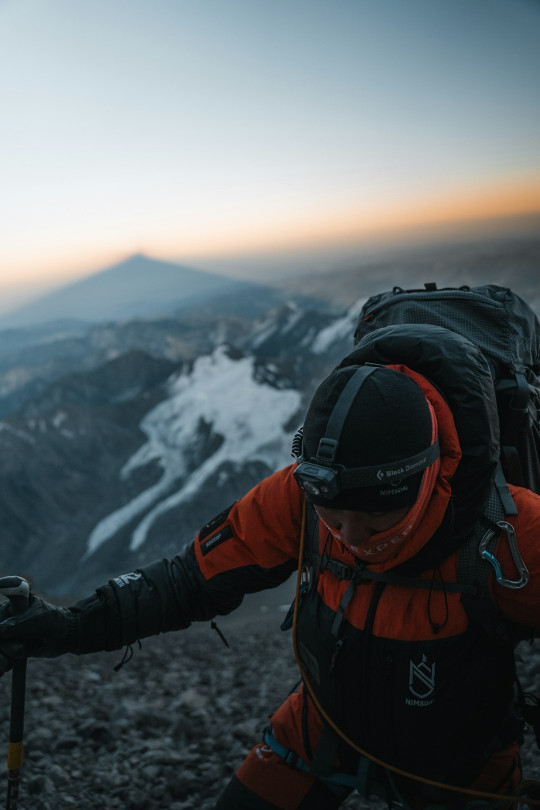 A man with a backpack climbing up a mountain