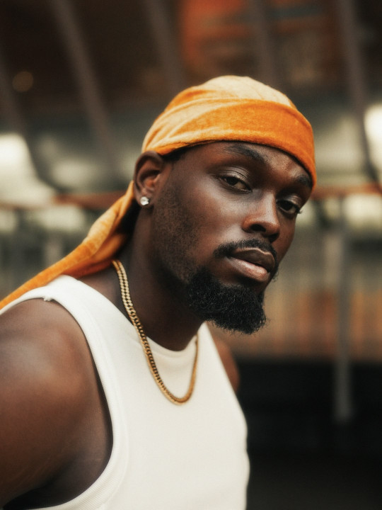 A man in a white tank top and a yellow towel on his head