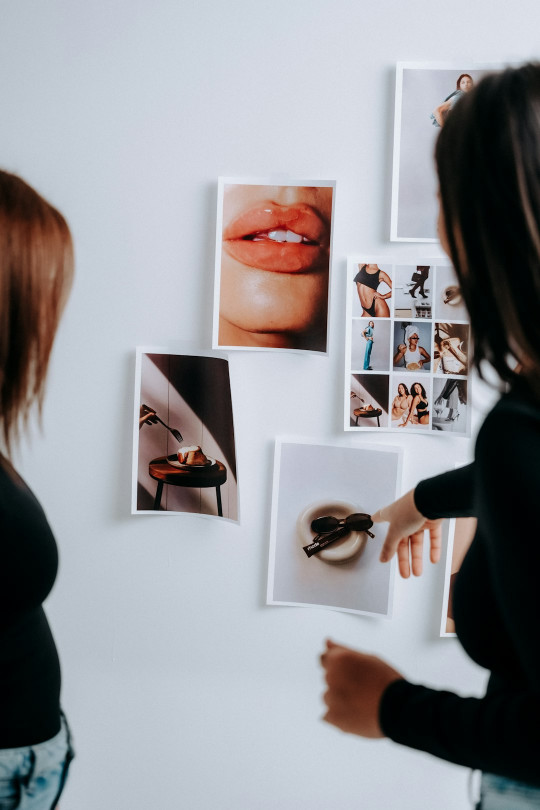 A woman pointing at pictures on a wall