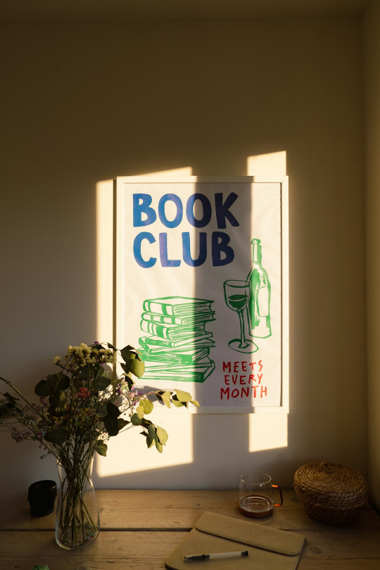 A vase of flowers sitting next to a book club sign