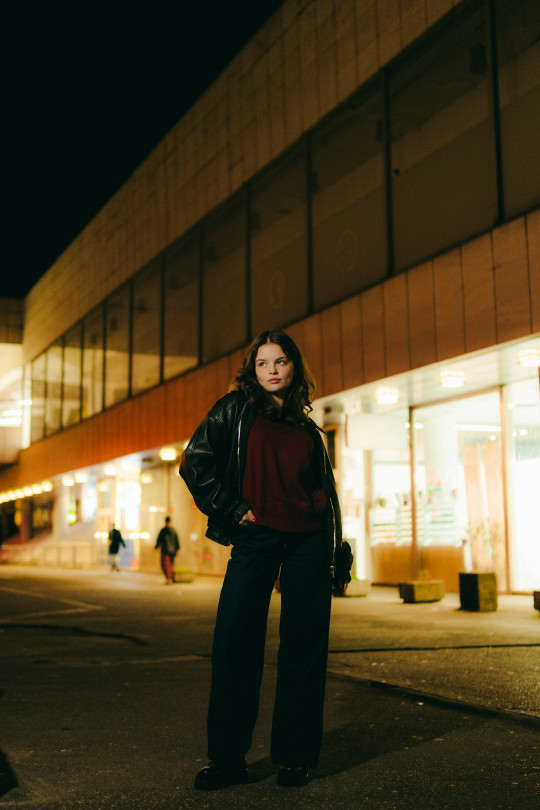 A woman standing in the middle of a street at night