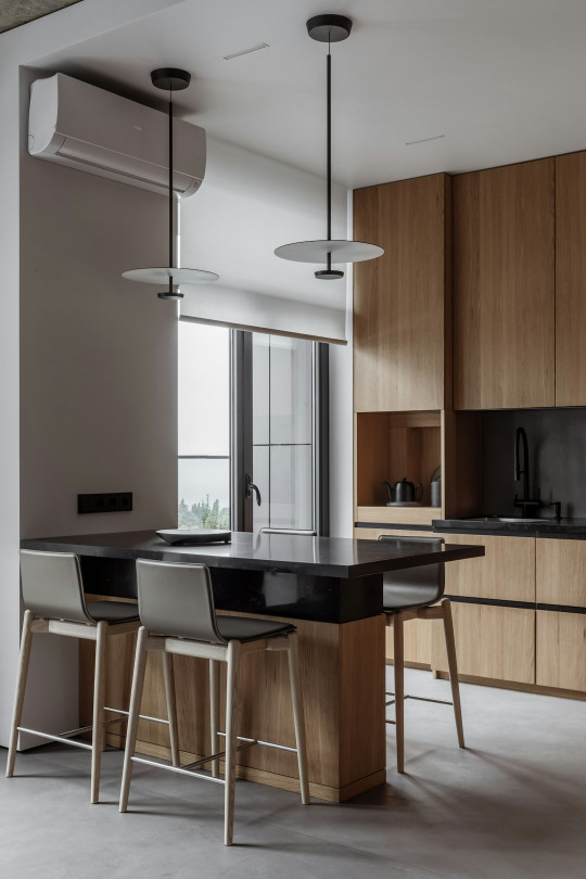 A kitchen with a table a stools and a window