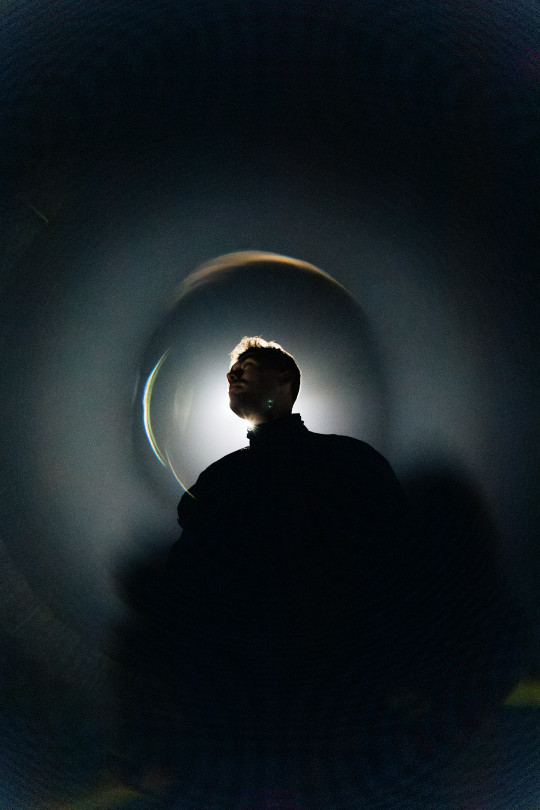 A man standing in front of a light in a dark room