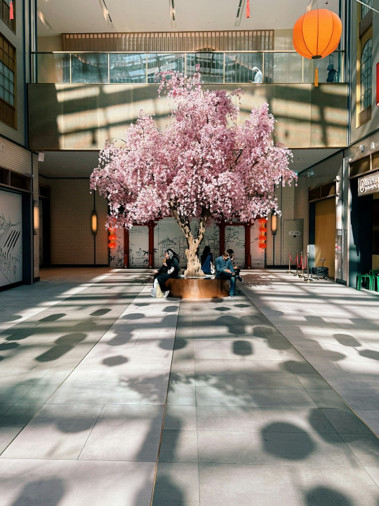 Two people sitting under a pink tree in a lobby