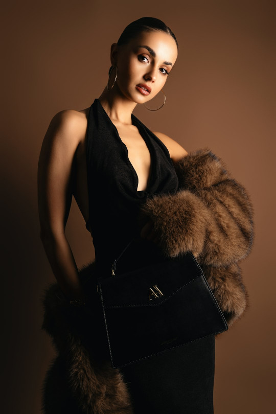 A woman in a black dress holding a fur stole