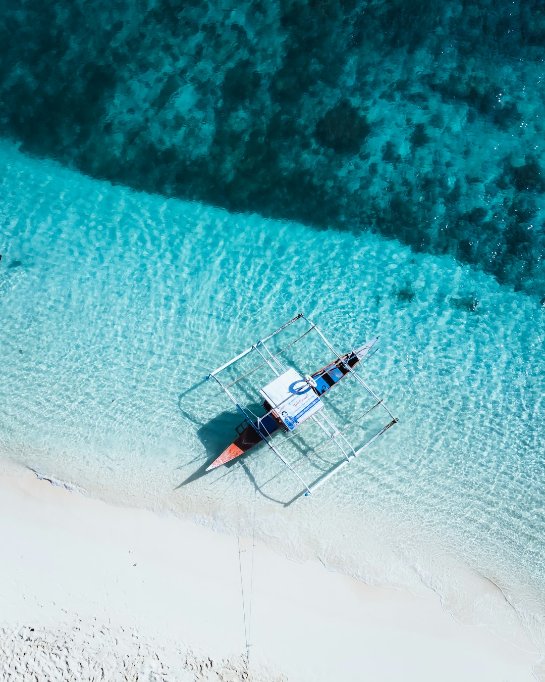 A boat floating on top of a sandy beach next to the ocean