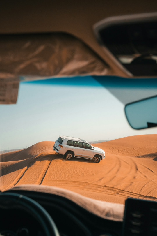 A white car driving on a desert road