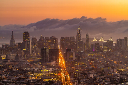 A view of a city at night from the top of a hill