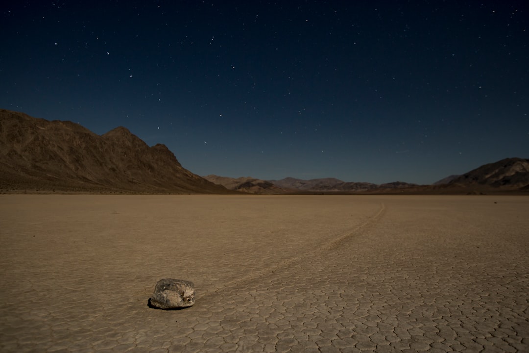 A rock in the middle of a desert at night