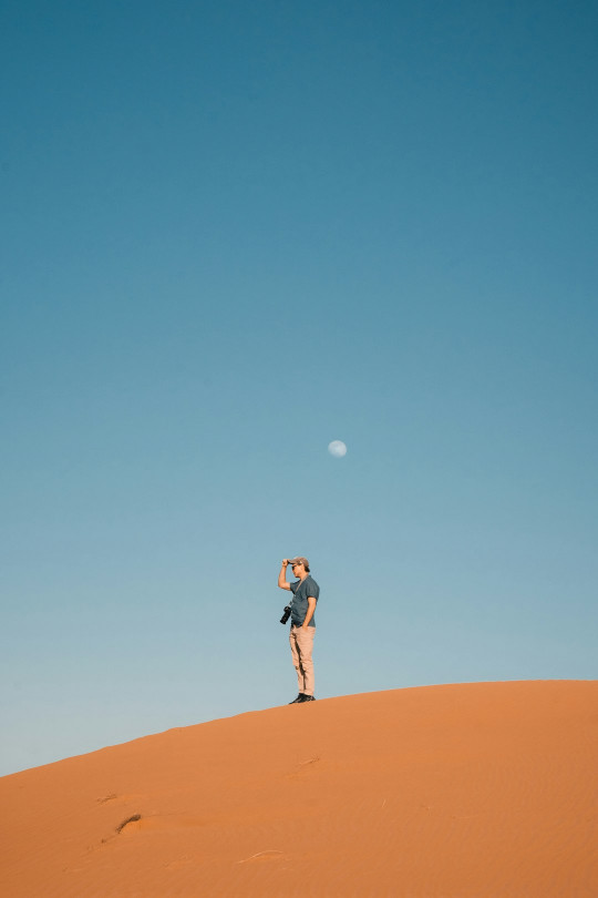 A person standing on top of a sand dune