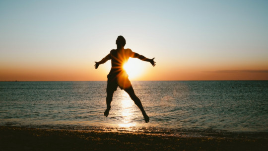 A person jumping into the air on a beach