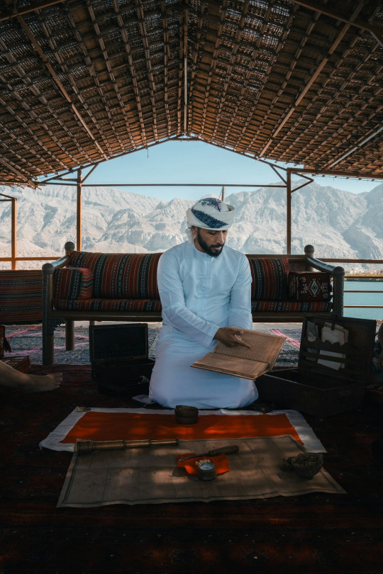 A man sitting on the ground reading a book