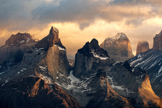 A mountain range covered in snow under a cloudy sky