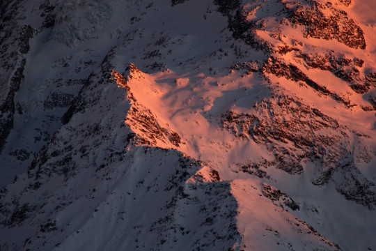 A very tall mountain covered in snow at sunset