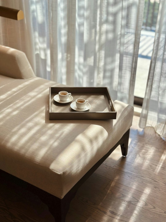 A tray with two cups of coffee on top of a bed