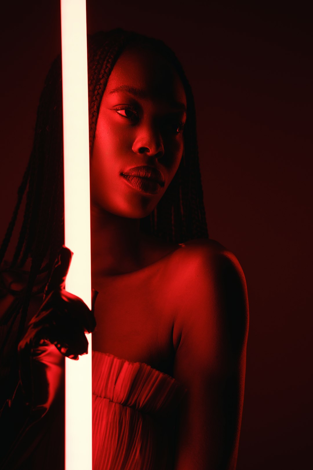 A woman standing behind a tall pole in a dark room