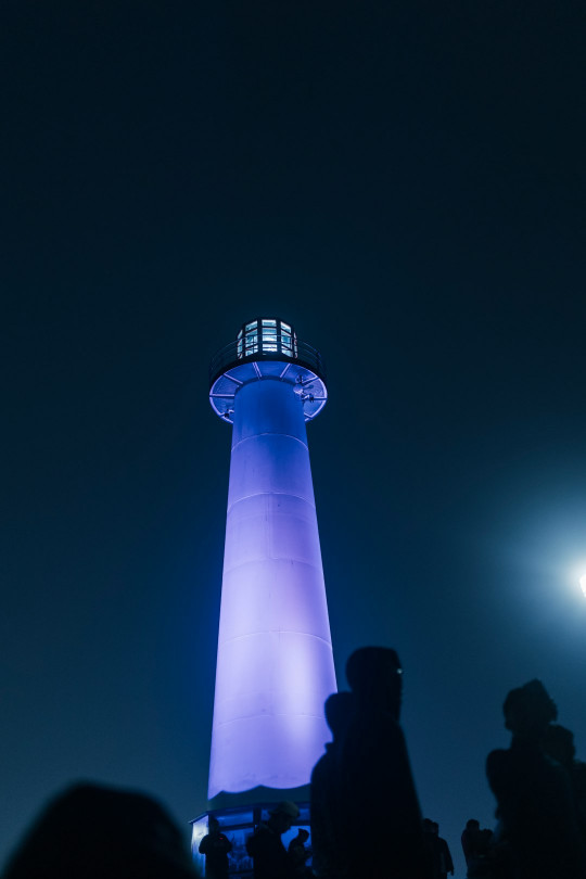 A group of people standing in front of a blue light tower