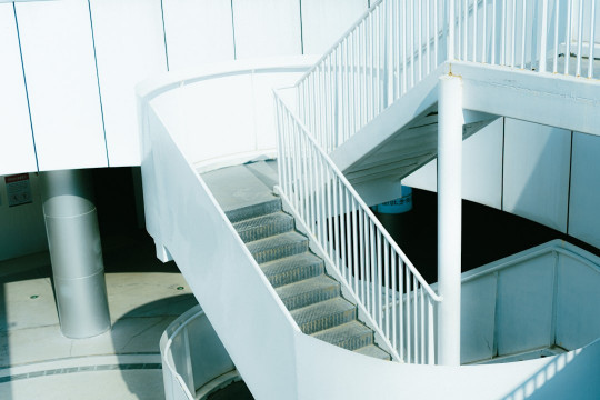 A spiral staircase in a building with a white railing