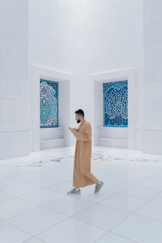 A man in a white room with two paintings on the wall