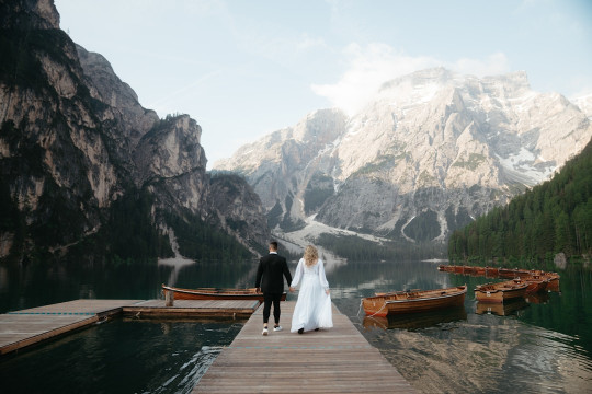 A bride and groom are standing on a dock