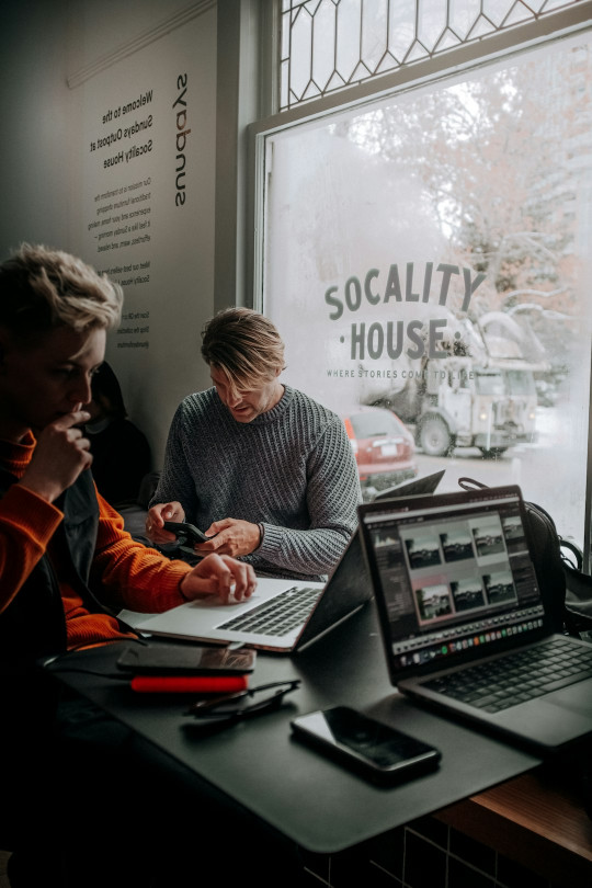 A group of people sitting at a table with laptops