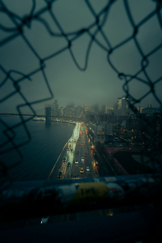 A view of a city from behind a chain link fence