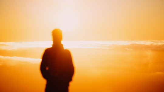 A silhouette of a person standing in front of the sun