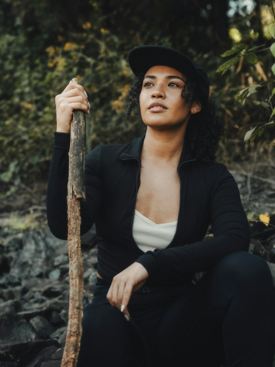 A woman sitting on a rock holding a stick