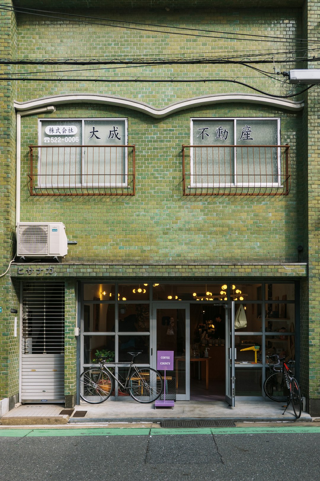 A green brick building with bicycles parked outside