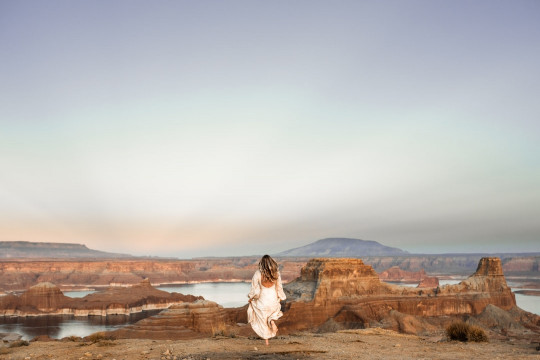 A woman in a white dress standing on top of a hill