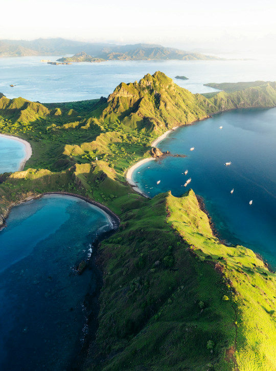 An aerial view of an island with several boats in the water