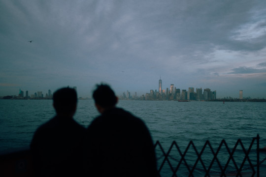 A couple of people standing next to a body of water