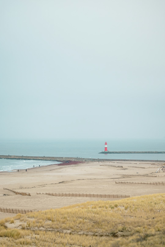 A beach with a light house in the distance