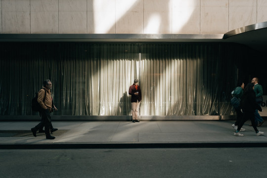 A group of people walking down a street next to a tall building