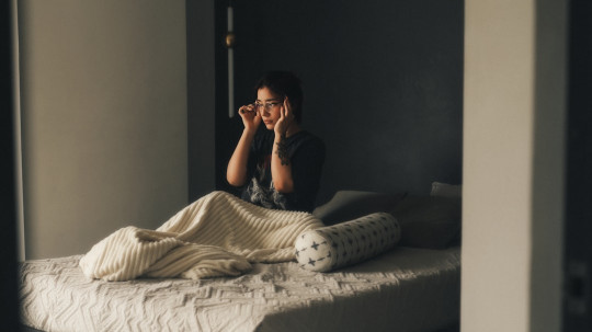 A person sitting on a bed in a room