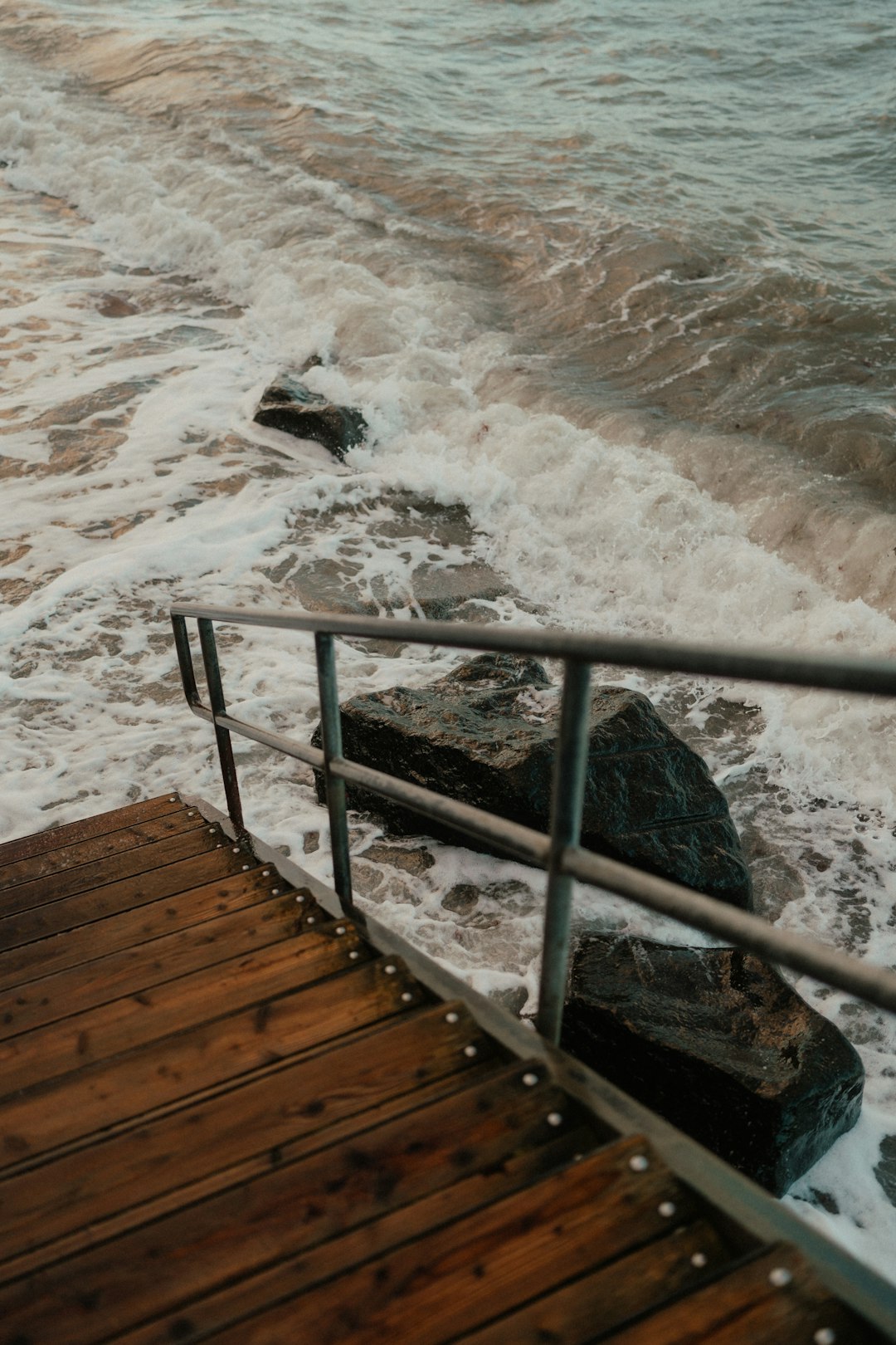 A person walking up a wooden ramp to the ocean