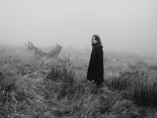 A black and white photo of a woman in a foggy field