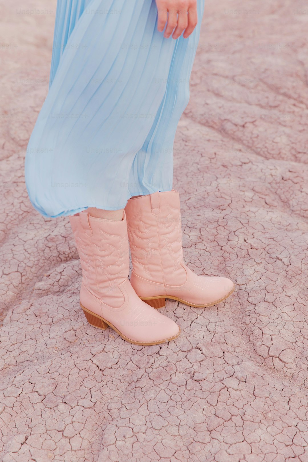 A woman in a blue dress and pink cowboy boots