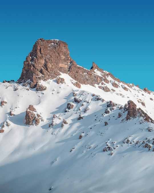 A mountain covered in snow under a blue sky