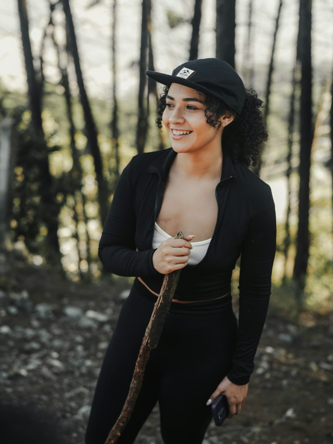 A woman in a black outfit holding a brown umbrella