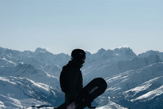 A snowboarder sitting on top of a snow covered mountain