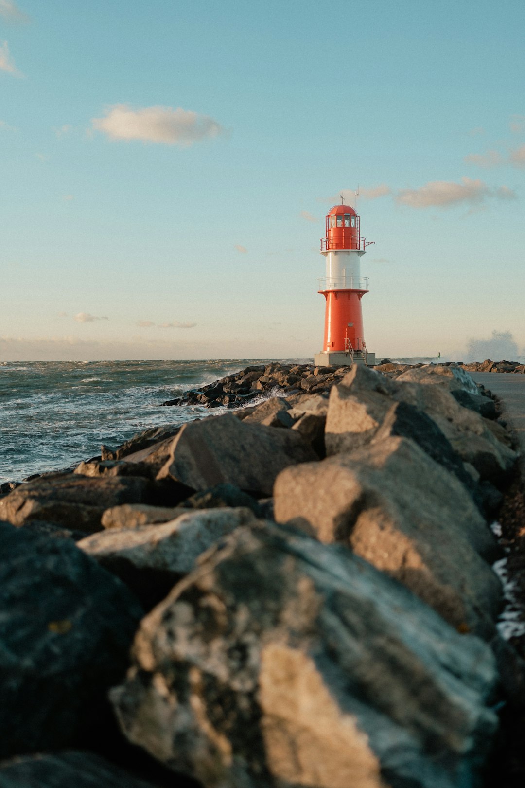 A red and white lighthouse sitting on top of a rocky shore