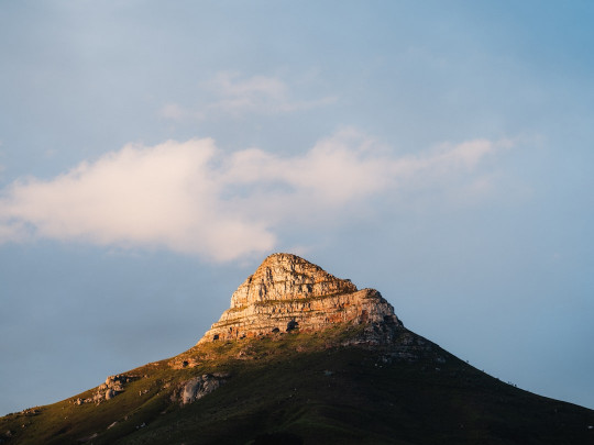 A very tall mountain with a sky in the background