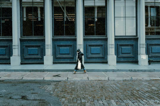 A woman walking down a street past a tall building