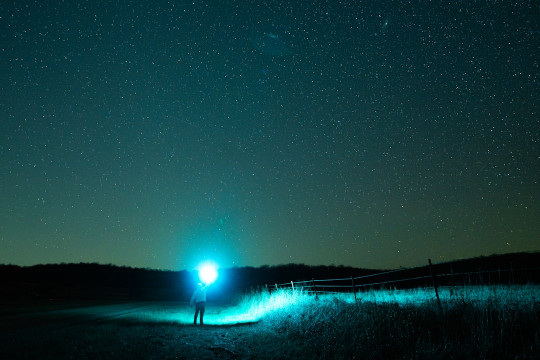 A person standing in the middle of a field at night