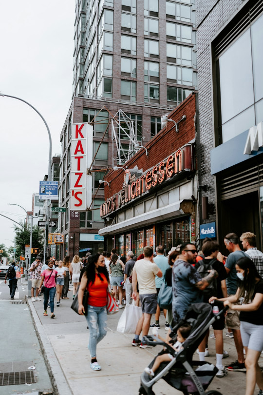 A crowd of people walking down a street next to tall buildings