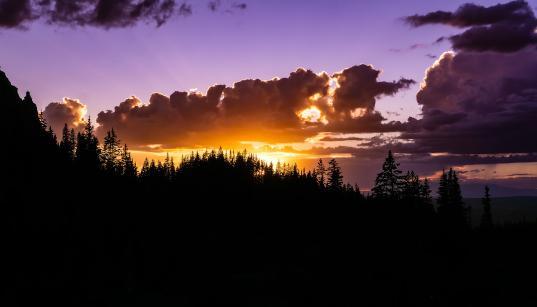 The sun is setting over the mountains and trees