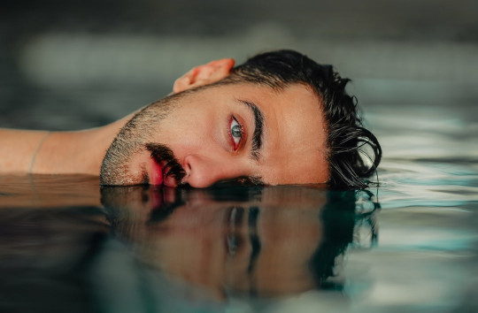 A man is floating in a pool of water