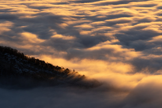 A mountain covered in clouds at sunset