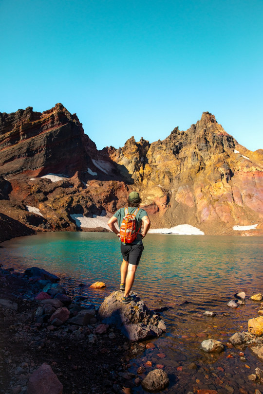 A man standing on top of a mountain next to a lake